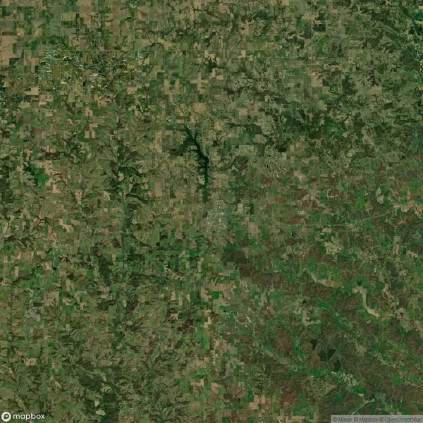 Aerial view of a rural landscape with patchy green fields, small wooded areas, and a few winding roads.