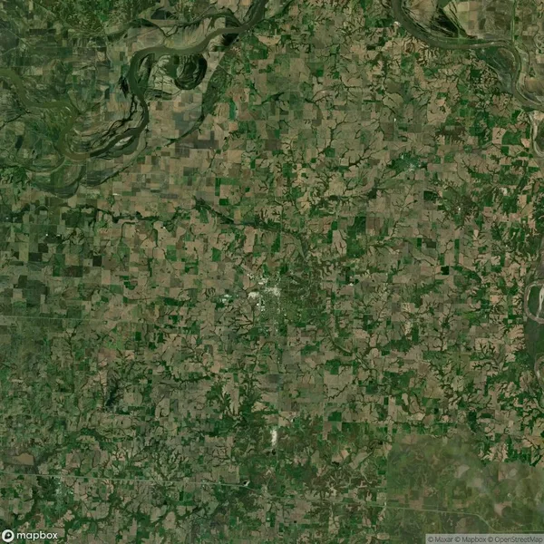 Aerial view of a rural landscape with patchwork fields, roads, and scattered vegetation.