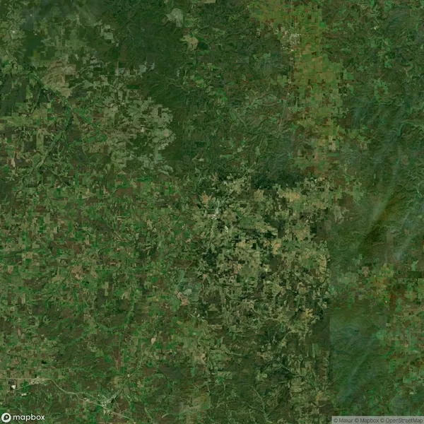 Aerial view of a large green landscape, showing a vast array of agricultural fields and patches of woodland, with a network of roads intersecting the area.