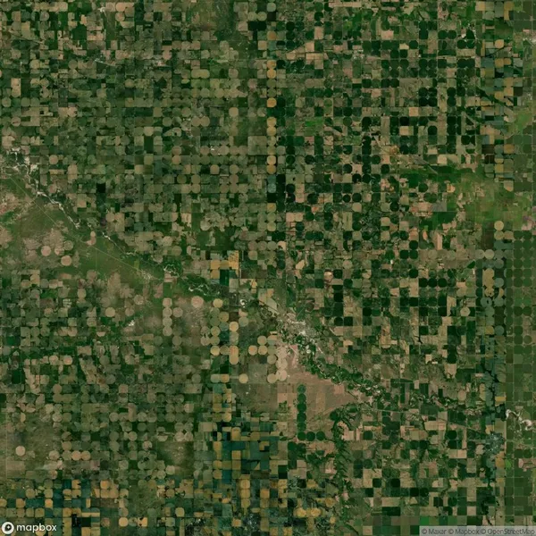 Aerial view of farmland with circular crop patterns, likely indicating center-pivot irrigation, interspersed with varied rectangular sections.