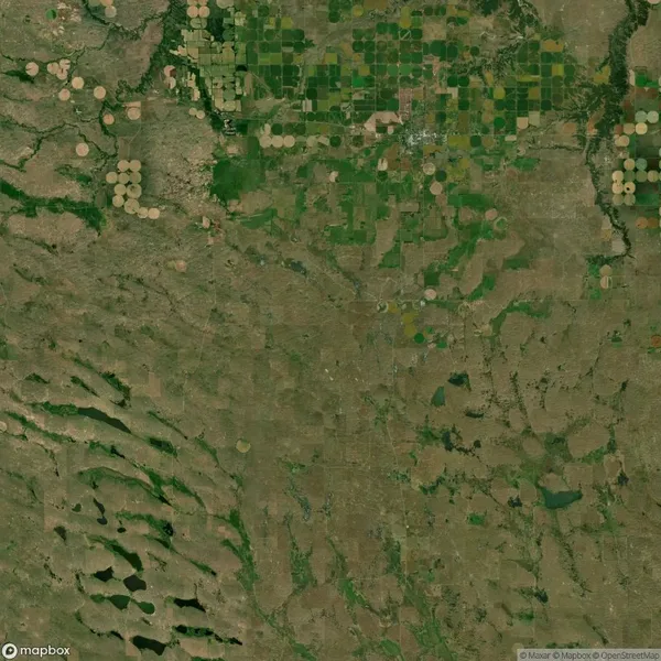 Satellite image showing a landscape with circular crop fields, green patches, and irregular terrain patterns.