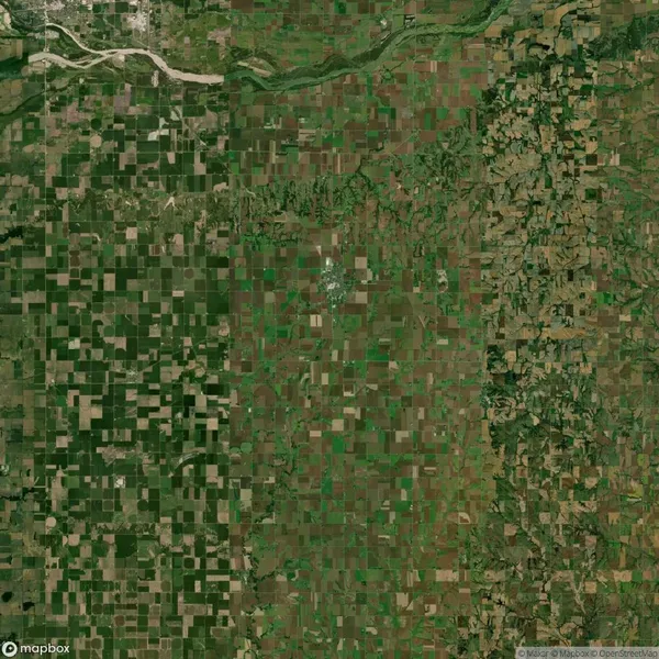 Aerial view of a landscape divided into a grid of rectangular agricultural fields, with a river winding through the upper portion and more varied terrain on the right side.