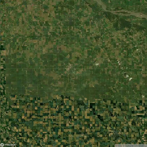Aerial view of a vast agricultural landscape with a patchwork of green fields and farms. A river is visible at the top right.