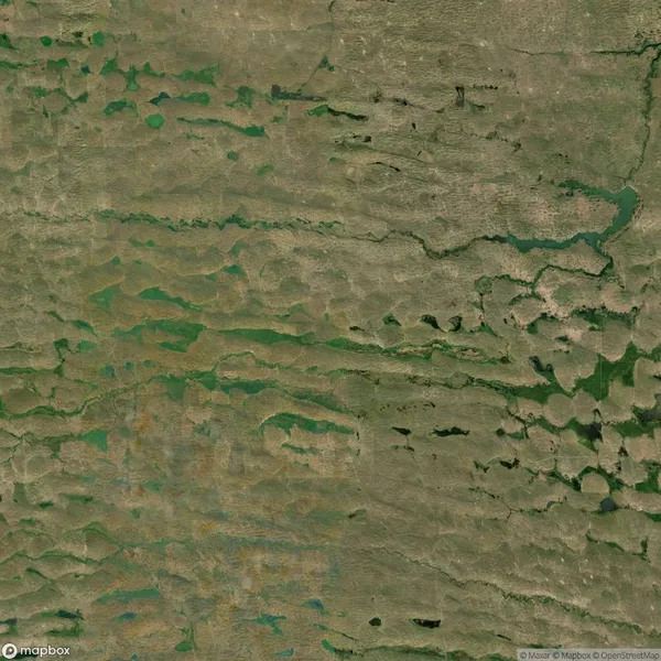 Aerial view of a hilly landscape with patches of green vegetation and scattered water bodies.