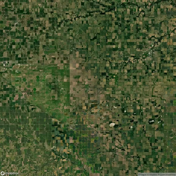 Satellite image showing a vast patchwork of agricultural fields, with varying shades of green and brown, forming a grid-like pattern across the landscape.