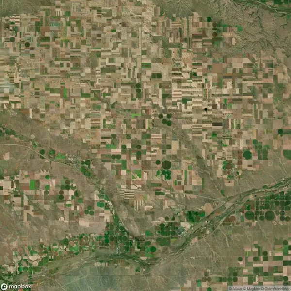 Aerial view of patchwork farmland with square and circular fields intersected by a river running diagonally across the landscape.