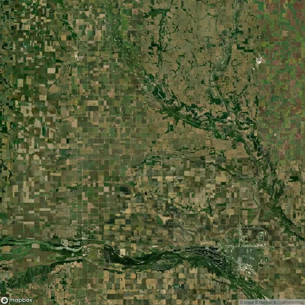 Aerial view of a landscape featuring a grid of agricultural fields, meandering rivers, and a developed urban area in the lower right corner.