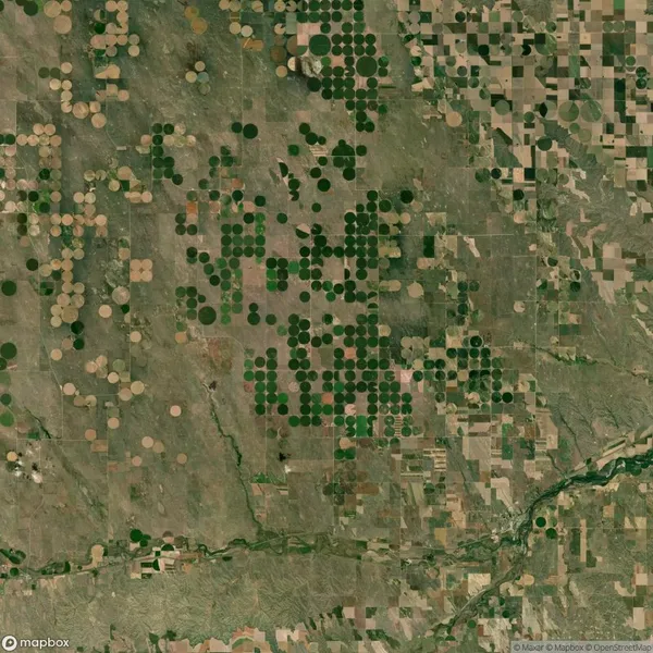 Aerial view of farmland with circular crop patterns and a river running through the lower right corner.
