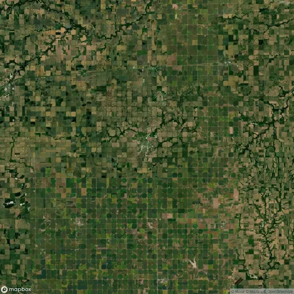 Aerial view of a vast, patchwork landscape featuring square and rectangular agricultural fields, intersected by various natural and man-made lines and patterns.