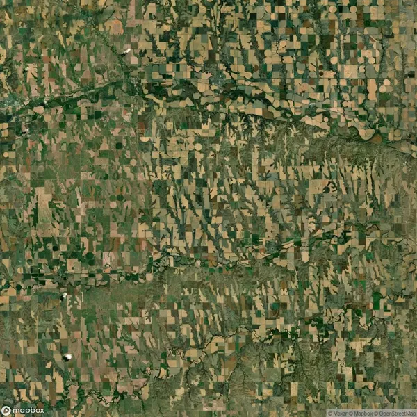 Aerial view of a patchwork landscape with various geometric agricultural fields, including circular and rectangular shapes, interspersed with patches of greenery and a meandering river.