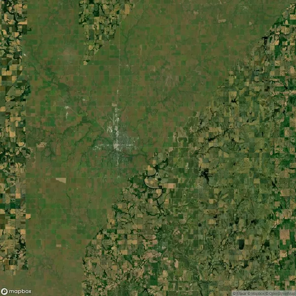 Aerial view of a patchwork landscape featuring fields and greenery with irregular patterns and rectangular divisions, interspersed with sparse vegetation and some water bodies.