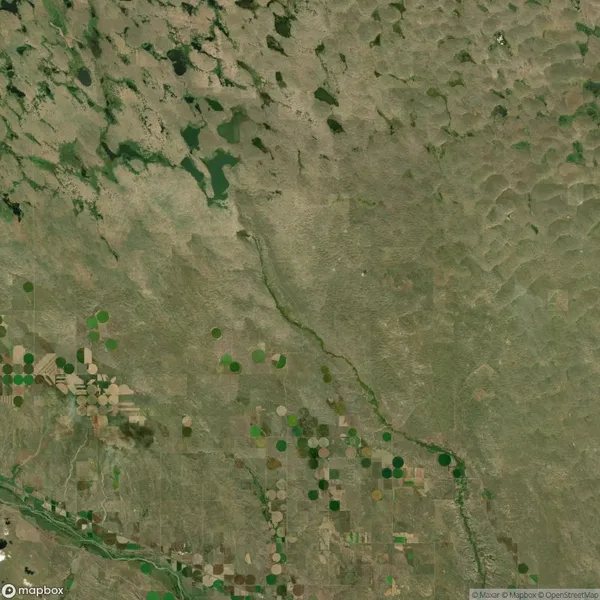 Aerial view of an agricultural landscape featuring circular crop fields, irregular patches of land, and a river running diagonally through the lower third of the image.