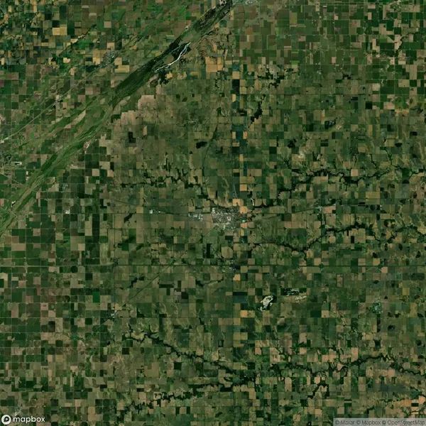 Aerial view of a rural landscape with a grid pattern of agricultural fields surrounding a small town, roads intersecting the area.