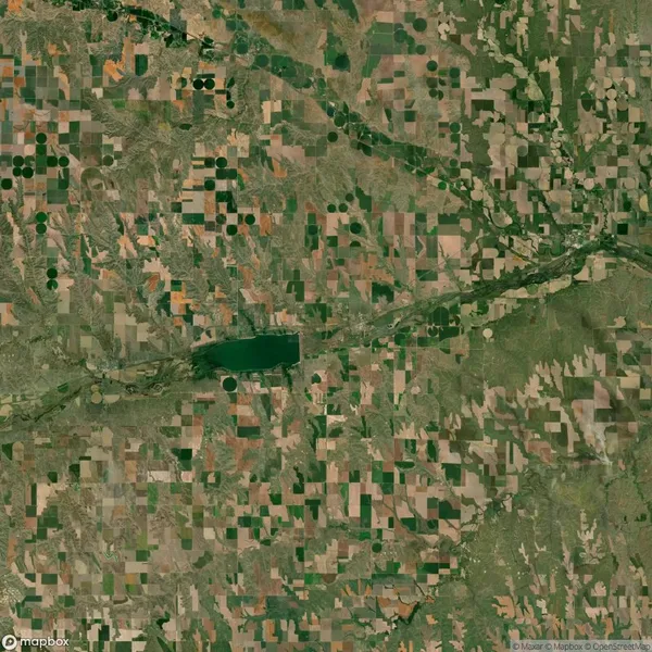 Aerial view of a landscape with a patchwork of agricultural fields, a winding river, and a large pond or lake near the center.