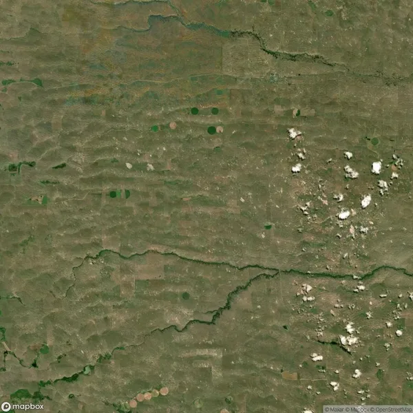 Aerial view of a green agricultural landscape with fields, scattered white clouds, and a winding river.