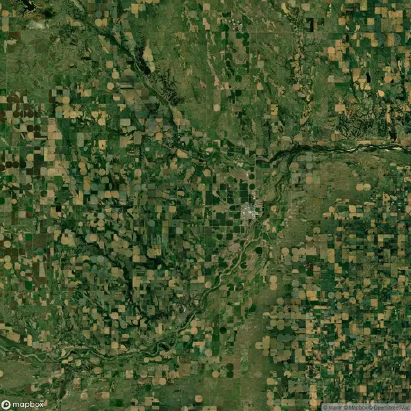 Aerial view of a landscape with patchwork fields, a winding river, and a small clustered settlement in the center.
