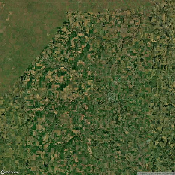 Aerial view of a vast patchwork landscape with fields and greenery interspersed with roads and sparse development.