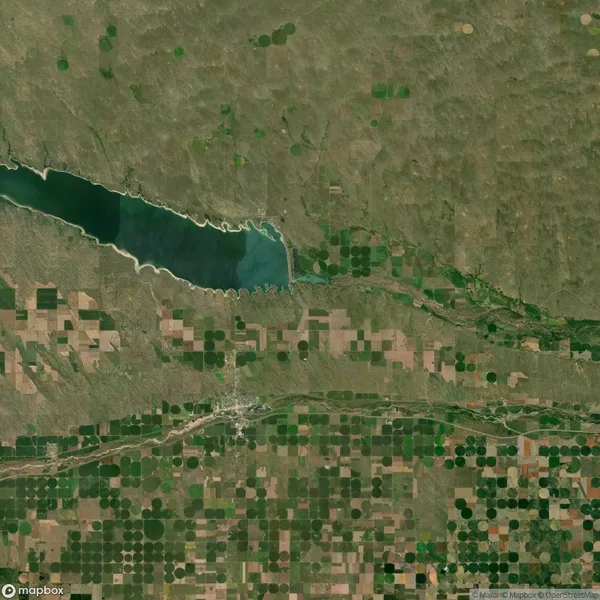 Satellite view of a large lake surrounded by patchwork agricultural fields and linear vegetation, indicating an irrigation system in a rural landscape.