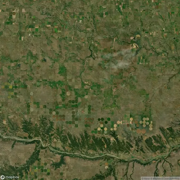 Aerial view of a rural landscape with various rectangular and circular agricultural fields, intersected by a winding river at the bottom.