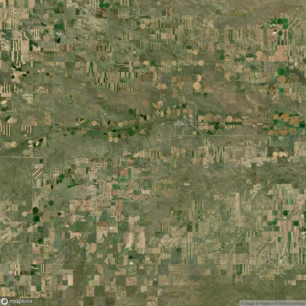 Aerial view of a patchwork of agricultural fields with various shapes and shades of green and brown in a rural area.