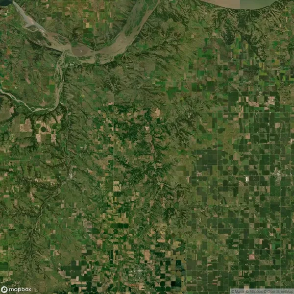 Aerial view of a rural landscape with a river at the top and a patchwork of green and brown agricultural fields below.