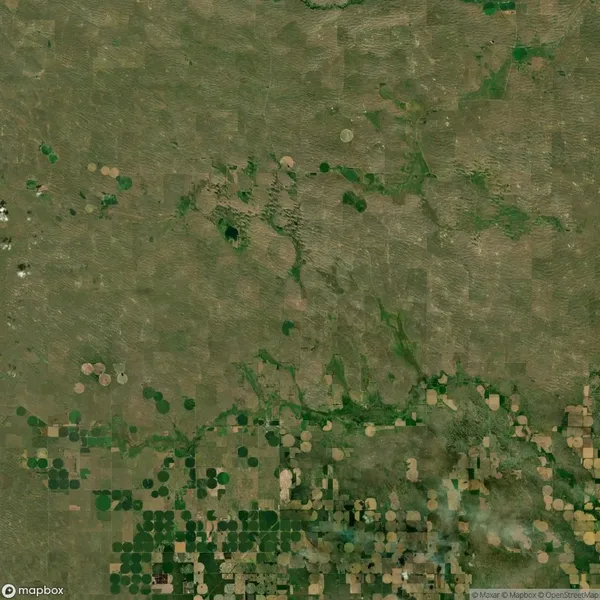 Aerial view of farmland with circular and square fields, displaying varying shades of green and brown.