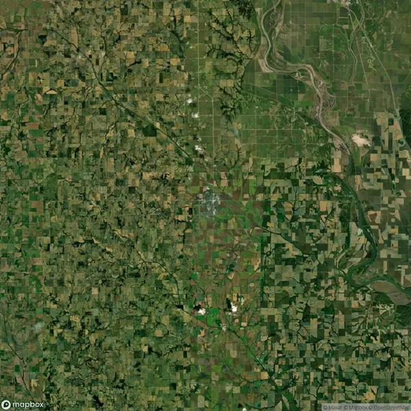 Satellite view of a green and brown patchwork landscape with fields, roads, and a winding river in the upper right corner.