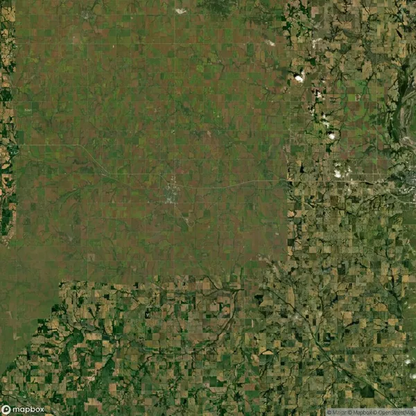 Aerial view of a patchwork of green and brown agricultural fields intersected by roads.