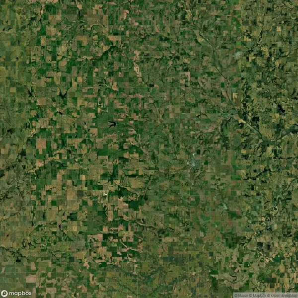 Aerial view of a rural landscape with a patchwork of green and brown fields, intersected by roads and small water bodies.