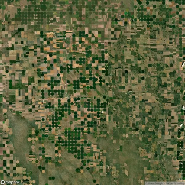 Aerial view of farmland with a patchwork of circular and square green fields, likely indicating irrigation systems and various crops.