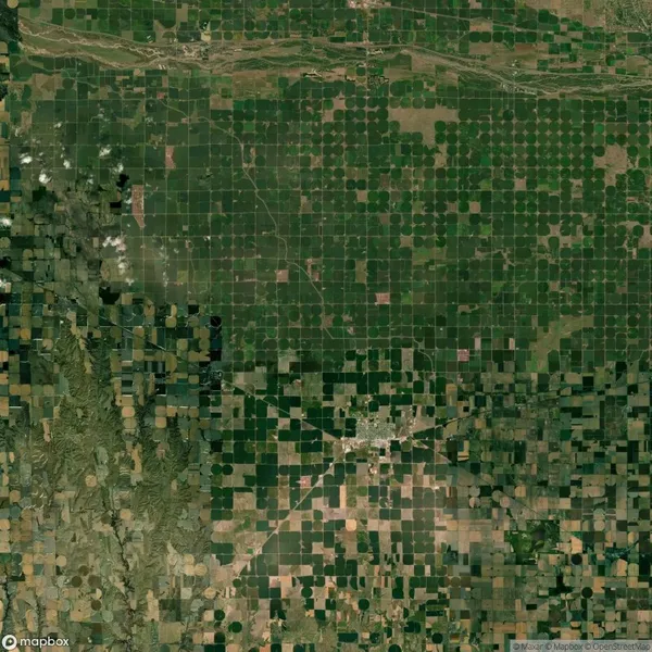 Aerial view of a landscape with a grid pattern of agricultural fields, a small town at the intersection, and a river running across the top.