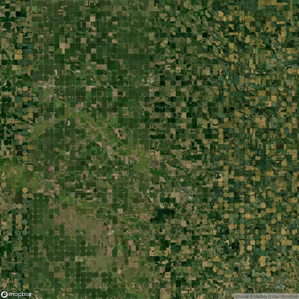 Aerial view of patchwork farmland. The landscape features a mix of square and circular fields, varying in shades of green and brown.
