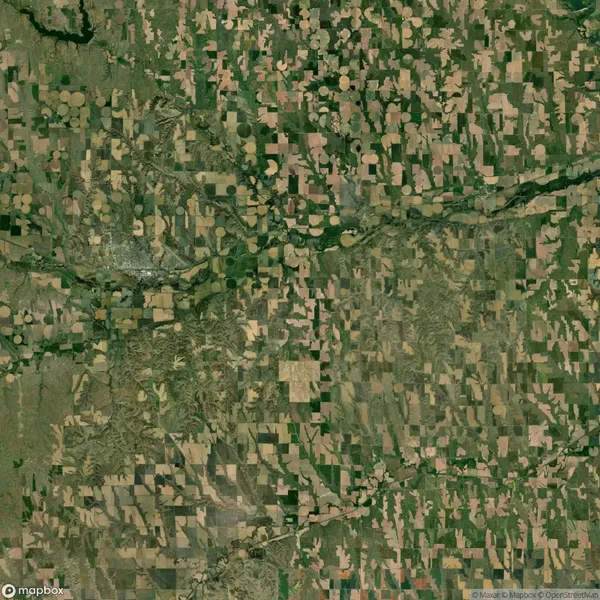 Aerial view of agricultural fields with a mix of circular and rectangular plots, intersected by roads and patches of greenery.