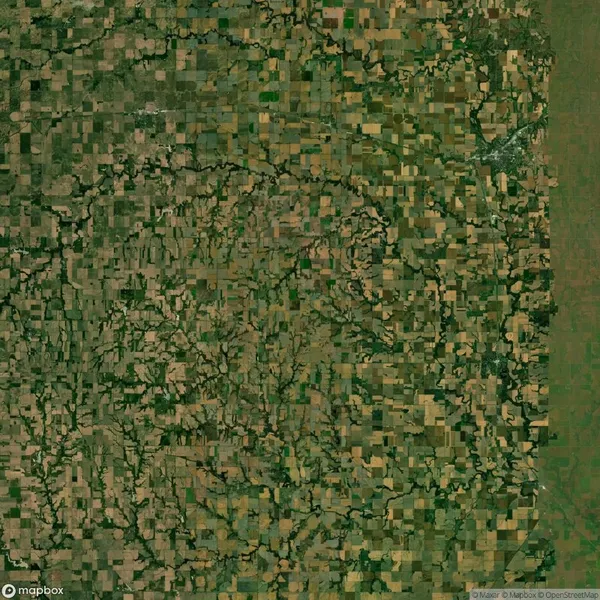 Aerial view of a vast patchwork landscape composed of agricultural fields varying in shades of green and brown, intersected by winding natural formations.