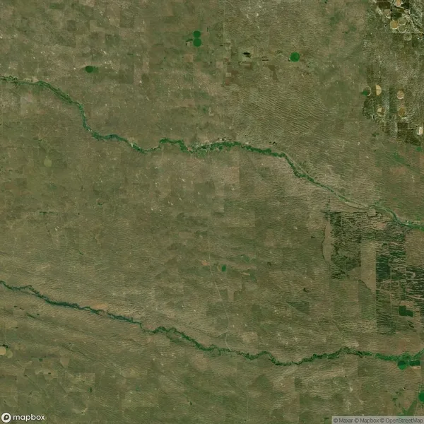 Aerial view of a green river meandering through a large expanse of farmland with scattered fields and patches.