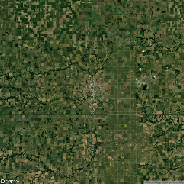 Aerial view of patchwork farmland and a central town surrounded by fields. Roads create a grid-like pattern, with some curving natural terrain breaking the uniformity.