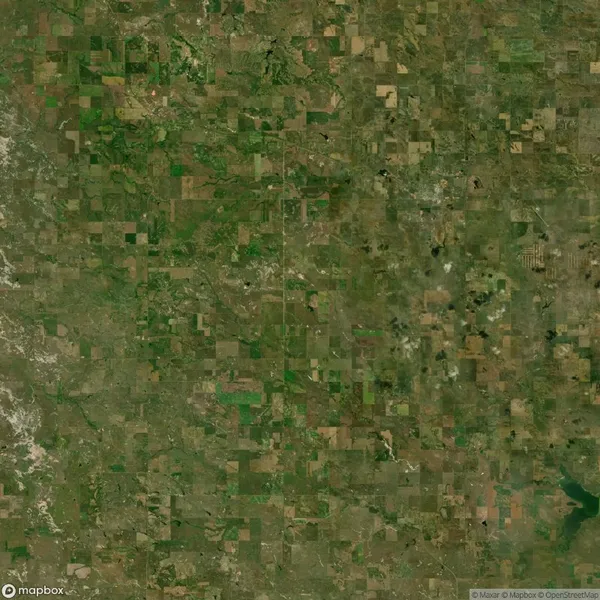 Aerial view of a rural landscape with a grid pattern of agricultural fields and patches of greenery and brown soil.