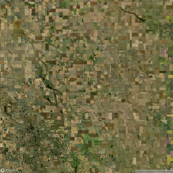 Aerial view of patchwork farmland with varying shades of green and brown fields, intersected by meandering rivers and scattered small towns.