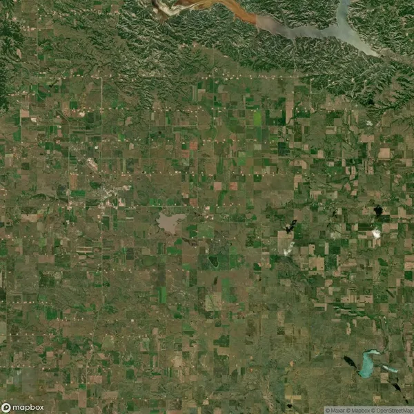 Satellite image showing a large expanse of farmland with a patchwork of fields and a river at the top.