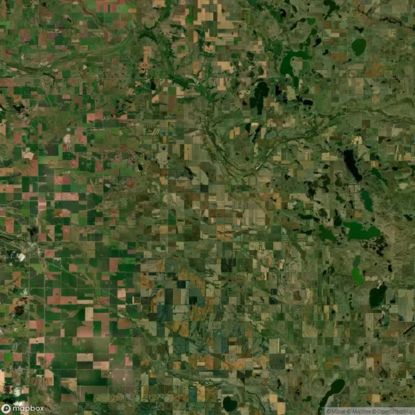 Aerial view of a patchwork landscape with rectangular fields, patches of green and brown, rivers, and scattered lakes.