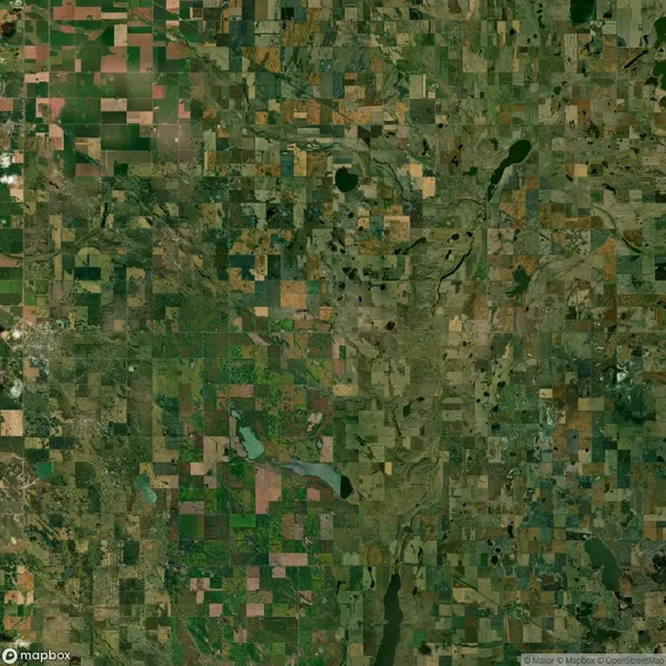 Aerial view of a patchwork landscape showing fields, green areas, and scattered water bodies, resembling a mosaic pattern.
