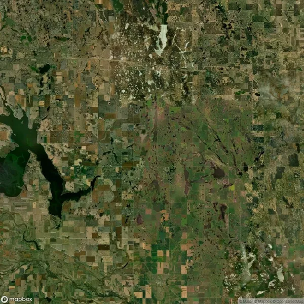 Satellite image showing a patchwork of agricultural fields and green areas with lakes scattered across the landscape.