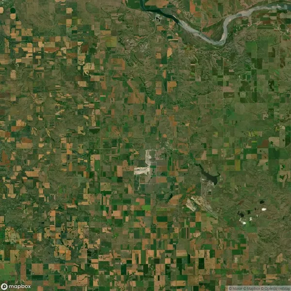 Aerial view of a patchwork landscape with a mix of green and brown agricultural fields, roads, and a curving river at the top.