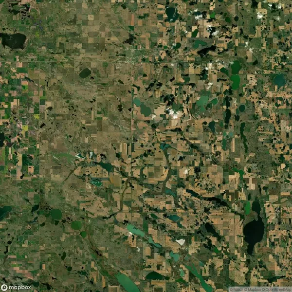 Aerial view of a rural landscape with patchwork fields, bodies of water, and scattered greenery.