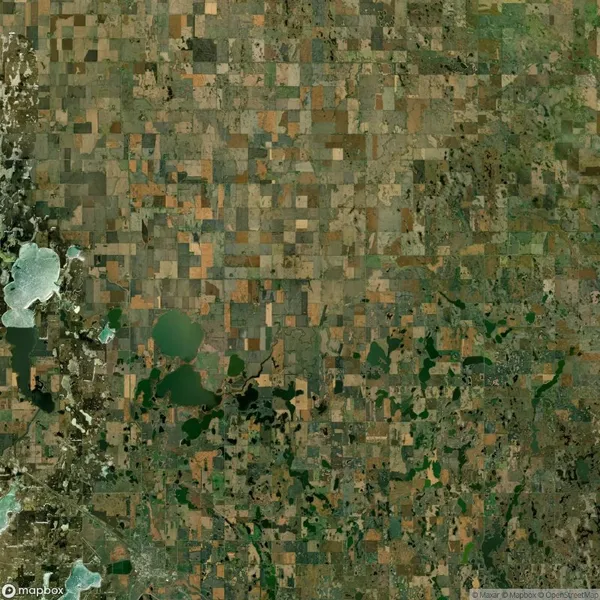 Aerial view of a rural landscape with patchwork fields, irregular green areas, and scattered bodies of water.