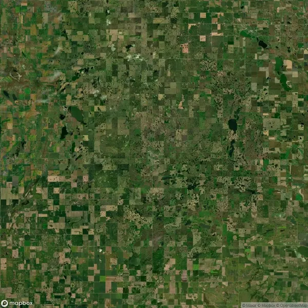 Aerial view of a vast patchwork of green and brown farmland fields, interspersed with small water bodies and patches of forest.