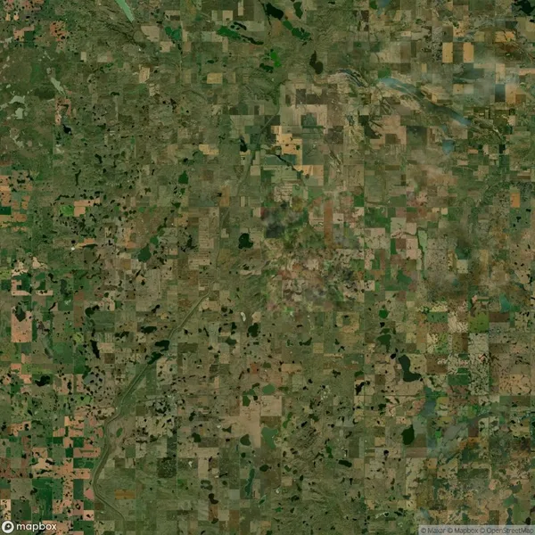 Aerial view of a rural landscape with a patchwork pattern of green and brown agricultural fields and scattered patches of forest.