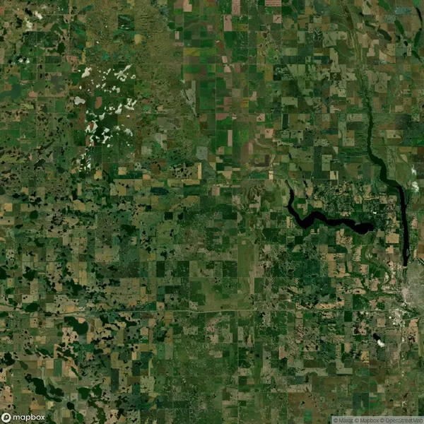Aerial view of a vast patchwork of agricultural fields, interspersed with scattered forests and a winding river, showcasing a rural landscape.