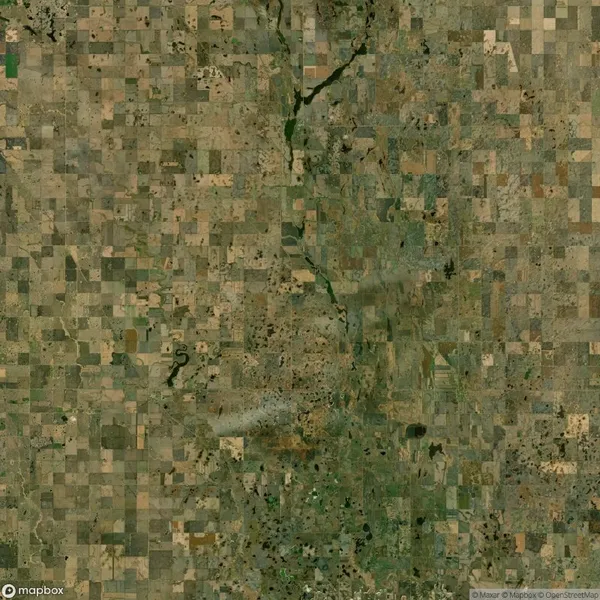 Aerial view of patchwork agricultural fields with varying shades of brown and green, intersected by winding roads and a slightly greenish river running vertically through the center.