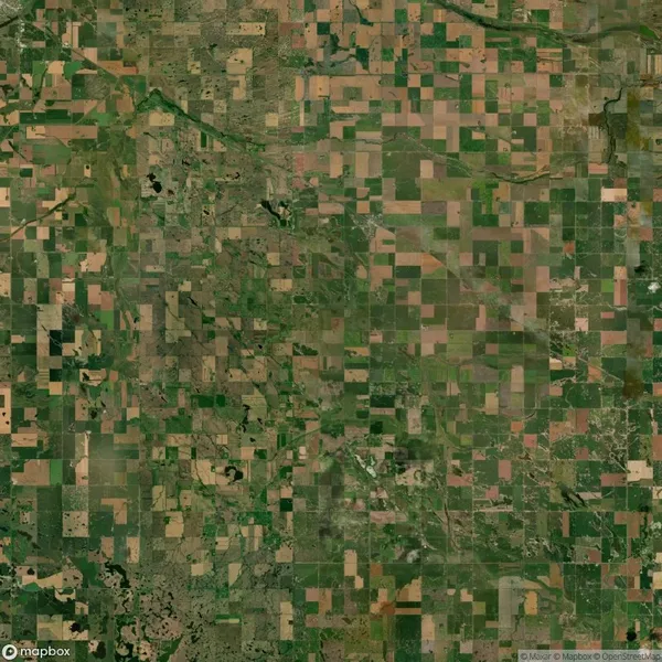 Aerial view of agricultural fields forming a patchwork pattern of green and brown squares and rectangles, interspersed with roads and natural vegetation.